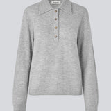 Strikket polo i grå med lange brede ærmer. Treemd polo har en stolpelukning og 4 knapper. Modellen er 175 cm og har en str. S/36 på.