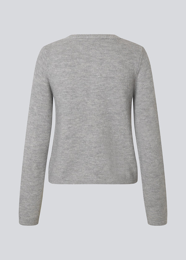 Lysegrå tætsiddende cardigan i blød strik. TreeMD cardigan har en rund hals og fine knapper i matchende farve, der understreger det enkle og feminine udtryk.
