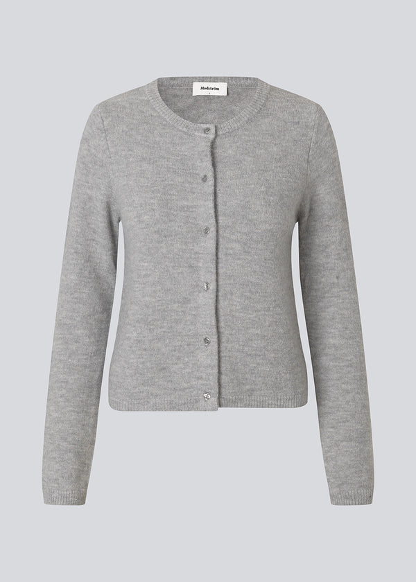 Lysegrå tætsiddende cardigan i blød strik. TreeMD cardigan har en rund hals og fine knapper i matchende farve, der understreger det enkle og feminine udtryk.
