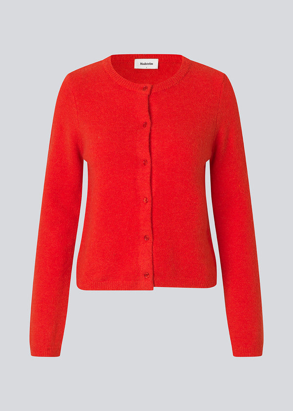 Rød tætsiddende cardigan i blød strik. TreeMD cardigan har en rund hals og fine knapper i matchende farve, der understreger det enkle og feminine udtryk.