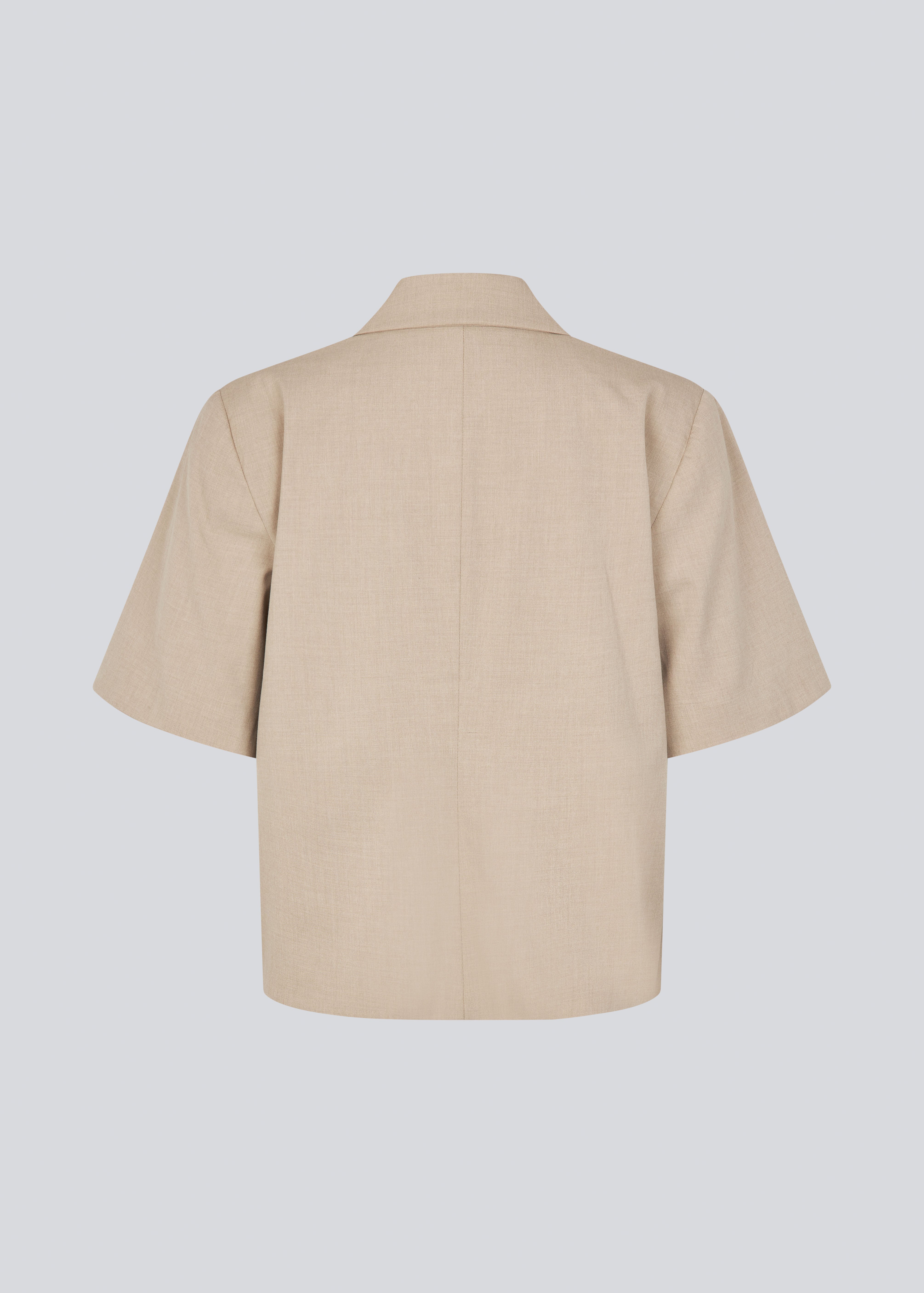 Kortærmet beige blazer med enkeltradet lukning. TuesdayMD SS Blazer har en krydsende knaplukning, krave, sidelommer og en falsk brystlomme – et moderne twist på en tidløs klassiker. Kan bæres lukket som en elegant top eller åben over en let bluse for et mere afslappet udtryk.&nbsp;