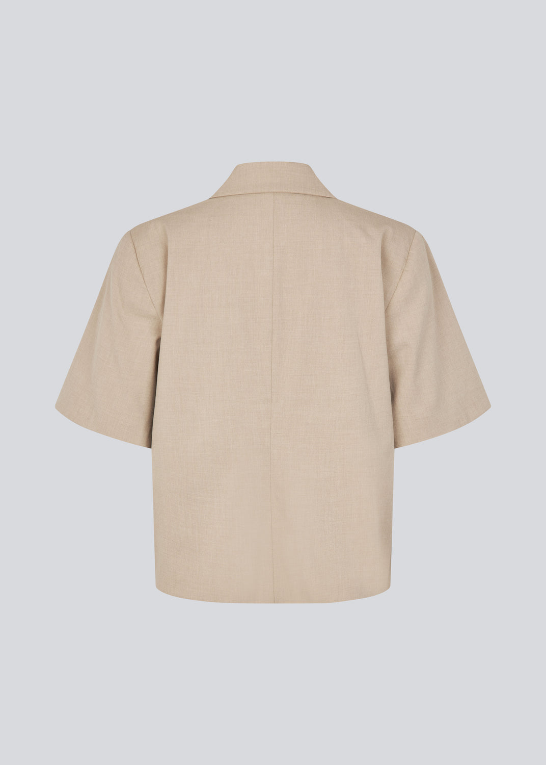 Kortærmet beige blazer med enkeltradet lukning. TuesdayMD SS Blazer har en krydsende knaplukning, krave, sidelommer og en falsk brystlomme – et moderne twist på en tidløs klassiker. Kan bæres lukket som en elegant top eller åben over en let bluse for et mere afslappet udtryk.&nbsp;