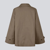 Kort jakke i brun med trenchcoat-inspiration. Umamd Jacket har skjortekrave, knappelukning, sidelommer og justerbar elastik forneden – et moderne bud på en klassisk silhuet.

Materiale:
97% Bomuld
3% Elastan

Foer:
100% Polyester