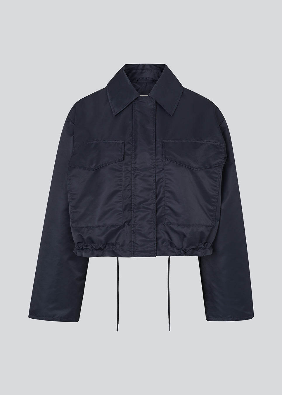 Kort jakke i navy med moderne og praktiske detaljer. Ulrikkemd jacket har en klassisk krave, store frontlommer med klap, justerbar snøre i taljen og er designet i glansfuldt nylon, der giver et stilrent og sporty look. Modellen er 175 cm og en str. S/36 på.

Materiale:
100% Nylon

Foer:
100% Polyester

Fyld:
100% Polyester