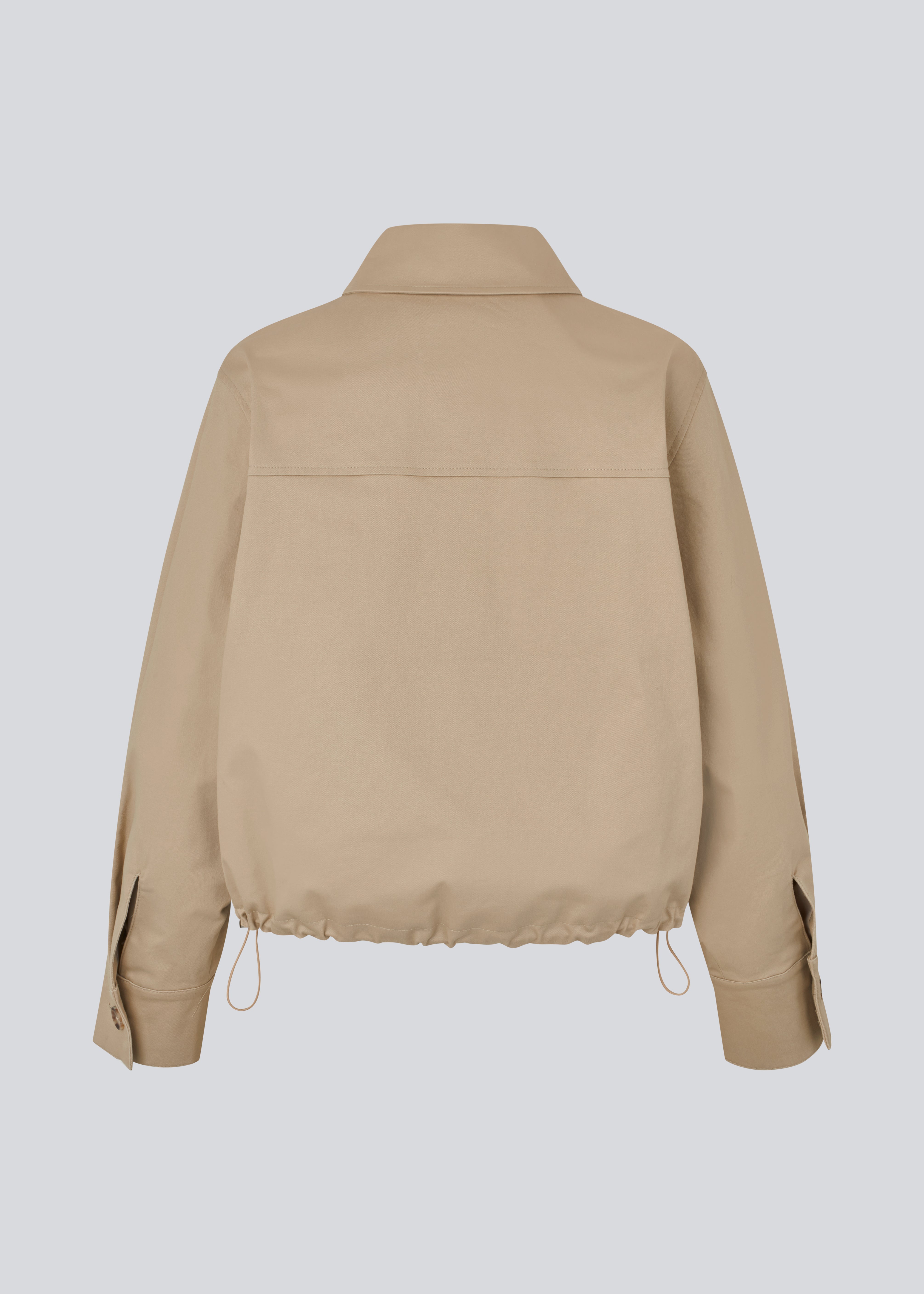 Kort beige jakke i trenchcoat look. Umamd jacket har skjortekrave, sidelommer, knappelukning og justerbar elastik i bunden. Modellen er 175 cm og har en str. S/36 på.

Materiale:
97% Bomuld
3% Elastan

Foer:
100% Polyester