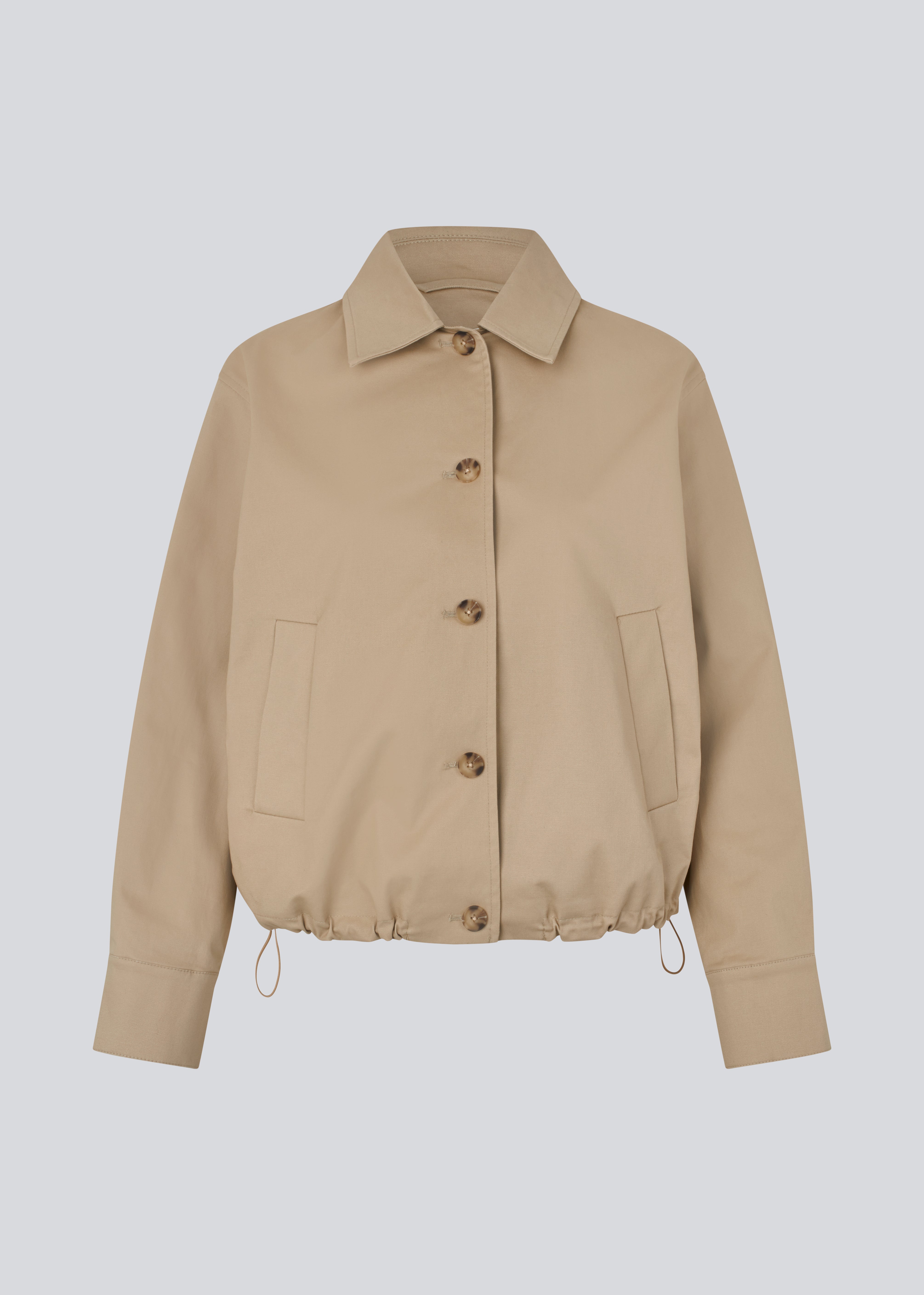 Kort beige jakke i trenchcoat look. Umamd jacket har skjortekrave, sidelommer, knappelukning og justerbar elastik i bunden. Modellen er 175 cm og har en str. S/36 på.

Materiale:
97% Bomuld
3% Elastan

Foer:
100% Polyester