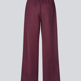Mørkerøde tracksuit pants med brede ben i 100% genanvendt polyester. Utopiamd pants har sidelommer, elastik i talje med snørre og logo.