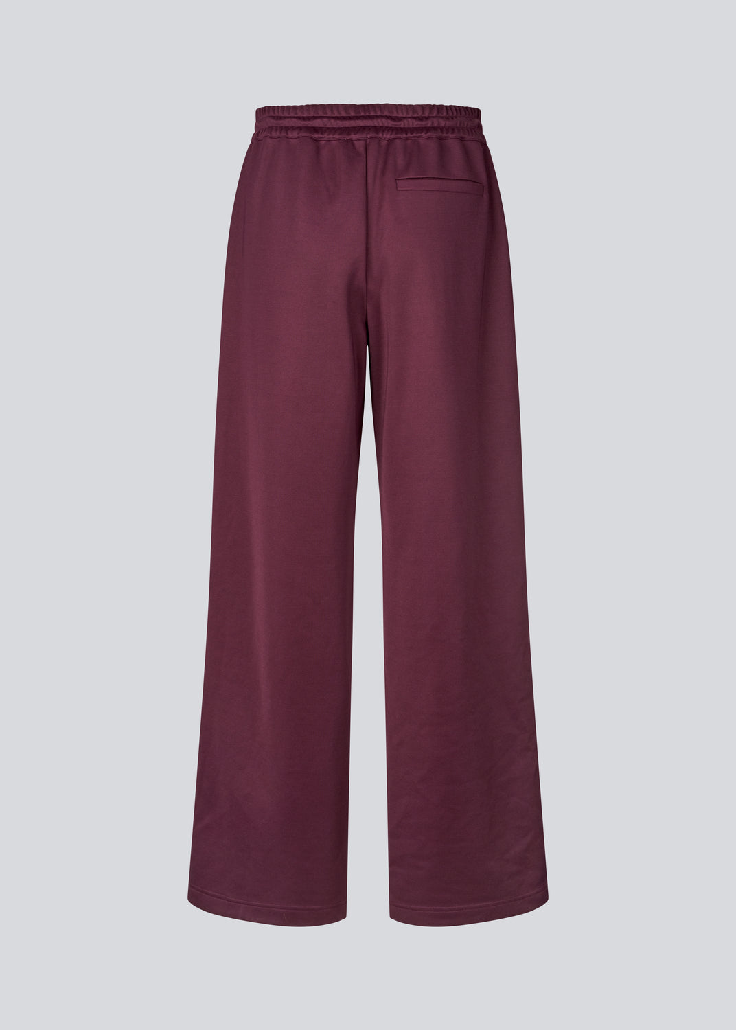 Mørkerøde tracksuit pants med brede ben i 100% genanvendt polyester. Utopiamd pants har sidelommer, elastik i talje med snørre og logo.