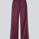 Mørkerøde tracksuit pants med brede ben i 100% genanvendt polyester. Utopiamd pants har sidelommer, elastik i talje med snørre og logo.