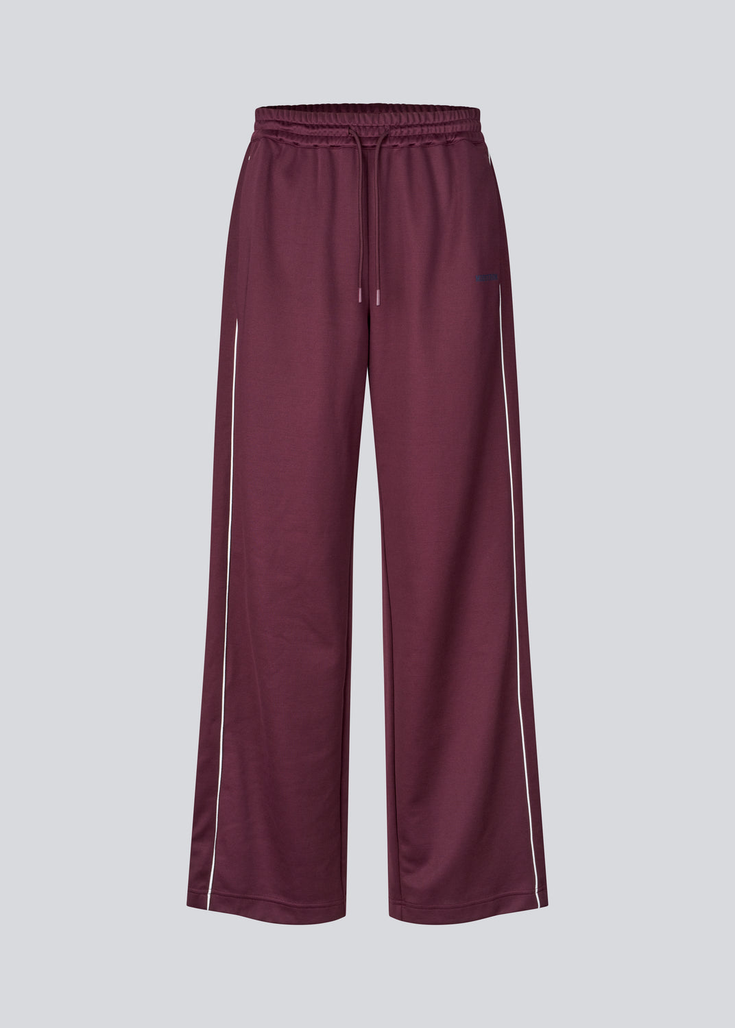 Mørkerøde tracksuit pants med brede ben i 100% genanvendt polyester. Utopiamd pants har sidelommer, elastik i talje med snørre og logo.