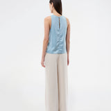 Ærmeløs blå top i glansfuld satin. Valdomd Top har rund halsudskæring, lodret sygningsdetalje foran og knappelukning i nakken for et elegant look. Fremstillet i 98 % genanvendt polyester.&nbsp;