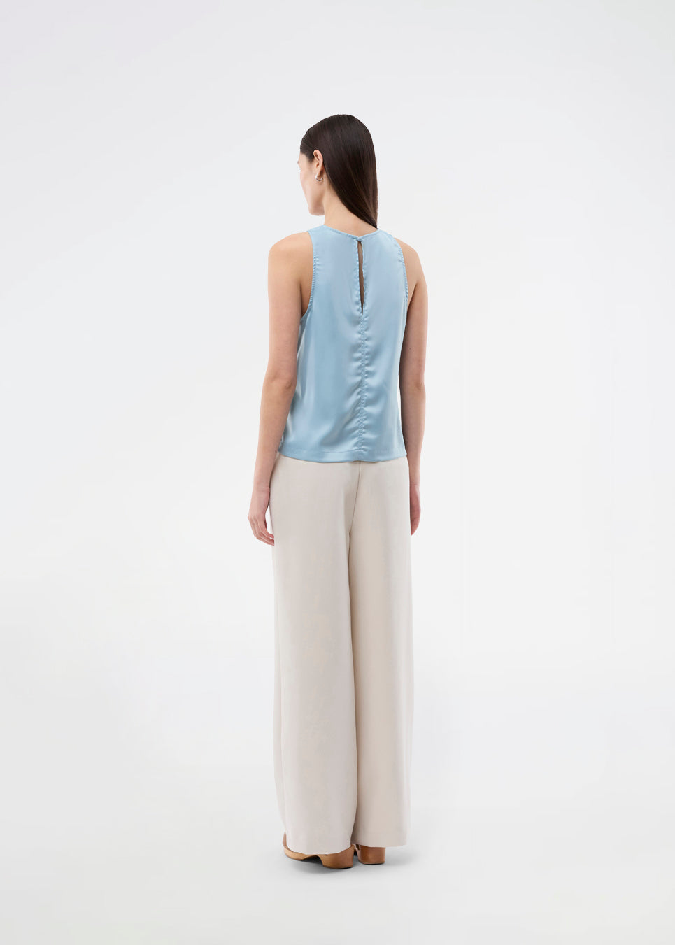 Ærmeløs blå top i glansfuld satin. Valdomd Top har rund halsudskæring, lodret sygningsdetalje foran og knappelukning i nakken for et elegant look. Fremstillet i 98 % genanvendt polyester.&nbsp;