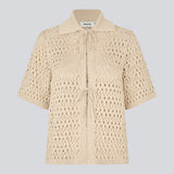 Elegant og let cardigan i et smukt strikket hulmønster. VesterMD cardigan har korte ærmer, krave og justerbar snørelukning foran, der giver et feminint og afslappet udtryk. Fremstillet i 100% økologisk bomuld for en blød og åndbar komfort.