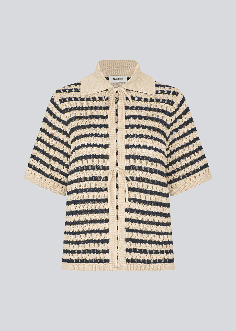 Elegant og let stribet cardigan i et smukt strikket hulmønster og striber. VesterMD stripe cardigan har korte ærmer, krave og justerbar snørelukning foran, der giver et feminint og afslappet udtryk. Fremstillet i 100% økologisk bomuld for en blød og åndbar komfort.