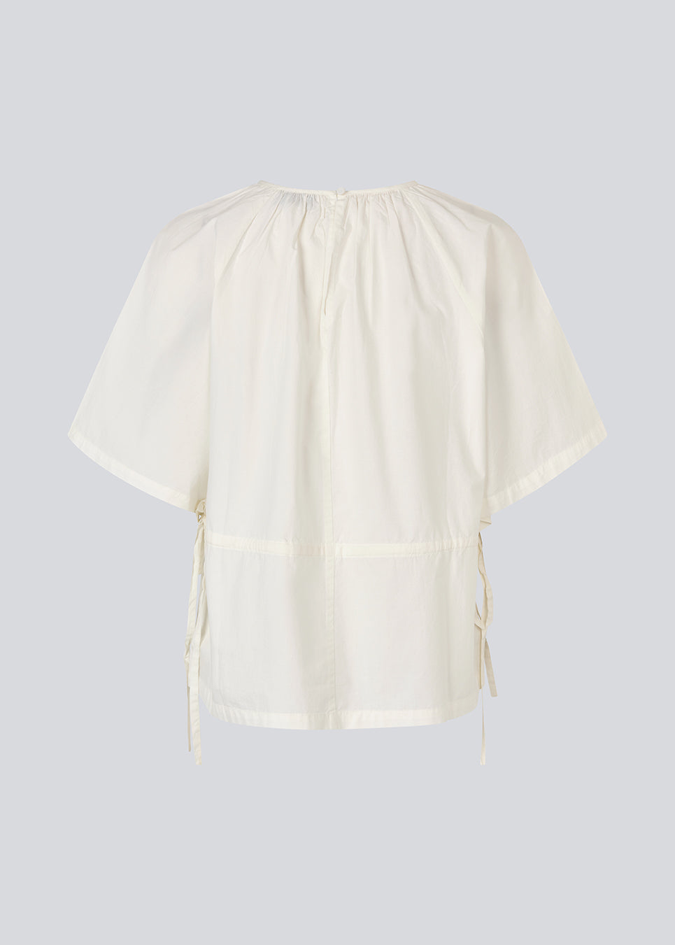 Let og feminin top i hvid. Vilbertmd top er designet med bløde læg ved halsen, korte vide ærmer og bindebånd i siden, der skaber et afslappet men raffineret udtryk. En elegant style, der nemt kan dresses op eller ned i den moderne garderobe.