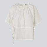 Let og feminin top i hvid. Vilbertmd top er designet med bløde læg ved halsen, korte vide ærmer og bindebånd i siden, der skaber et afslappet men raffineret udtryk. En elegant style, der nemt kan dresses op eller ned i den moderne garderobe.