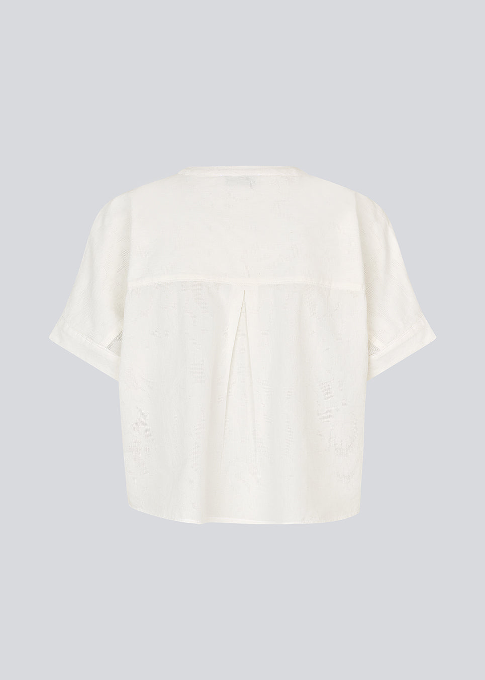 Kortærmet skjorte-bluse i hvid med ensfarvet print. VilleminMD shirt har knappelukning, rund halsudskæring og opsmøg på ærmerne, og længden går til buksekanten. Et tidløst og elegant valg, der nemt kan styles både til hverdag og aften.