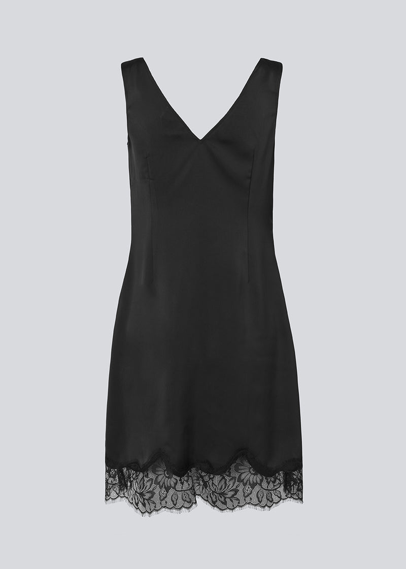 Kort sort satinkjole med blonde detaljer i bunden og over brystet. Vuemd Dress har brede stropper, krydsdetalje med blonder over brystet og en skjult lynlås i siden. En elegant og feminin style, der er perfekt til både hverdag og fest.