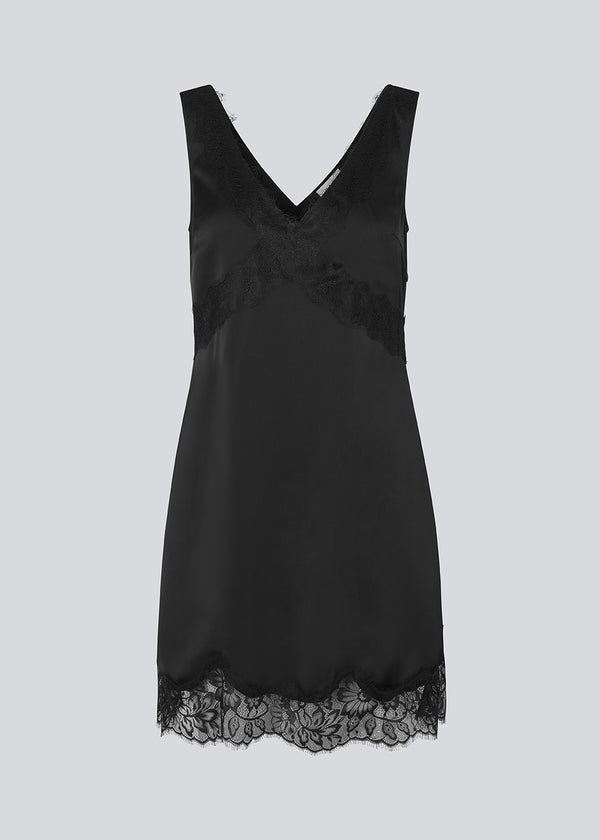 Kort sort satinkjole med blonde detaljer i bunden og over brystet. Vuemd Dress har brede stropper, krydsdetalje med blonder over brystet og en skjult lynlås i siden. En elegant og feminin style, der er perfekt til både hverdag og fest.