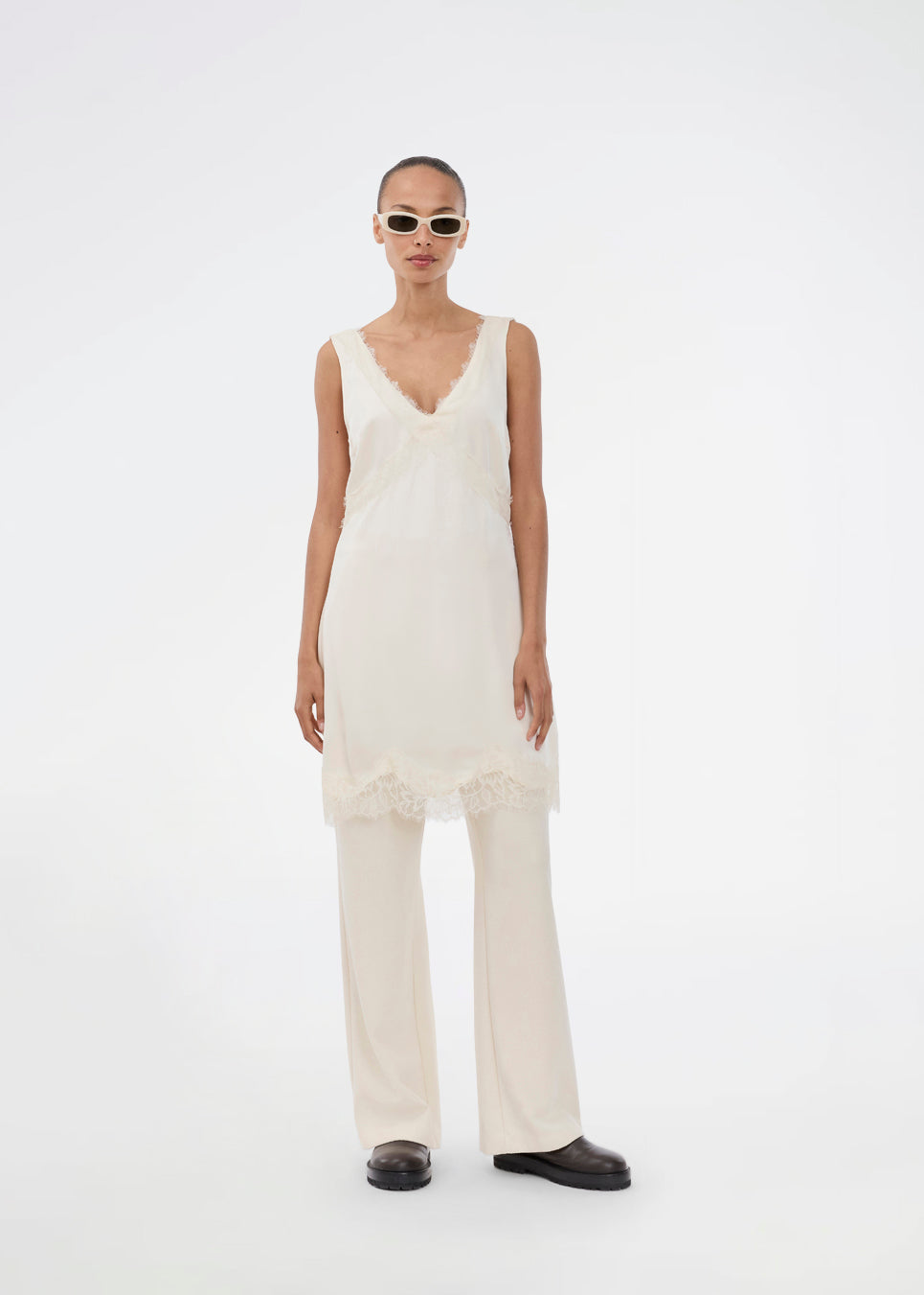 Kort hvid satin kjole med blonde detaljer. Vuemd Dress har brede stropper, krydsdetalje over brystet og en skjult lynlås i siden. En elegant og feminin style, der er perfekt til både hverdag og fest.