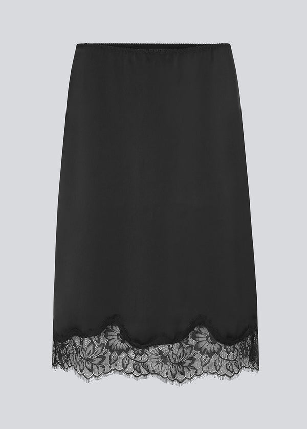 Sort satin nederdel med blondedetaljer i bunden. Vuemd skirt er knælang med eleastik i taljen og har en afslappet pasform. Ideel alene eller stylet som en del af en lag-på-lag styling.
