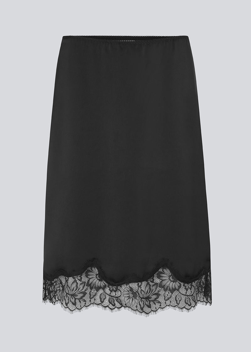 Sort satin nederdel med blondedetaljer i bunden. Vuemd skirt er knælang med eleastik i taljen og har en afslappet pasform. Ideel alene eller stylet som en del af en lag-på-lag styling.
