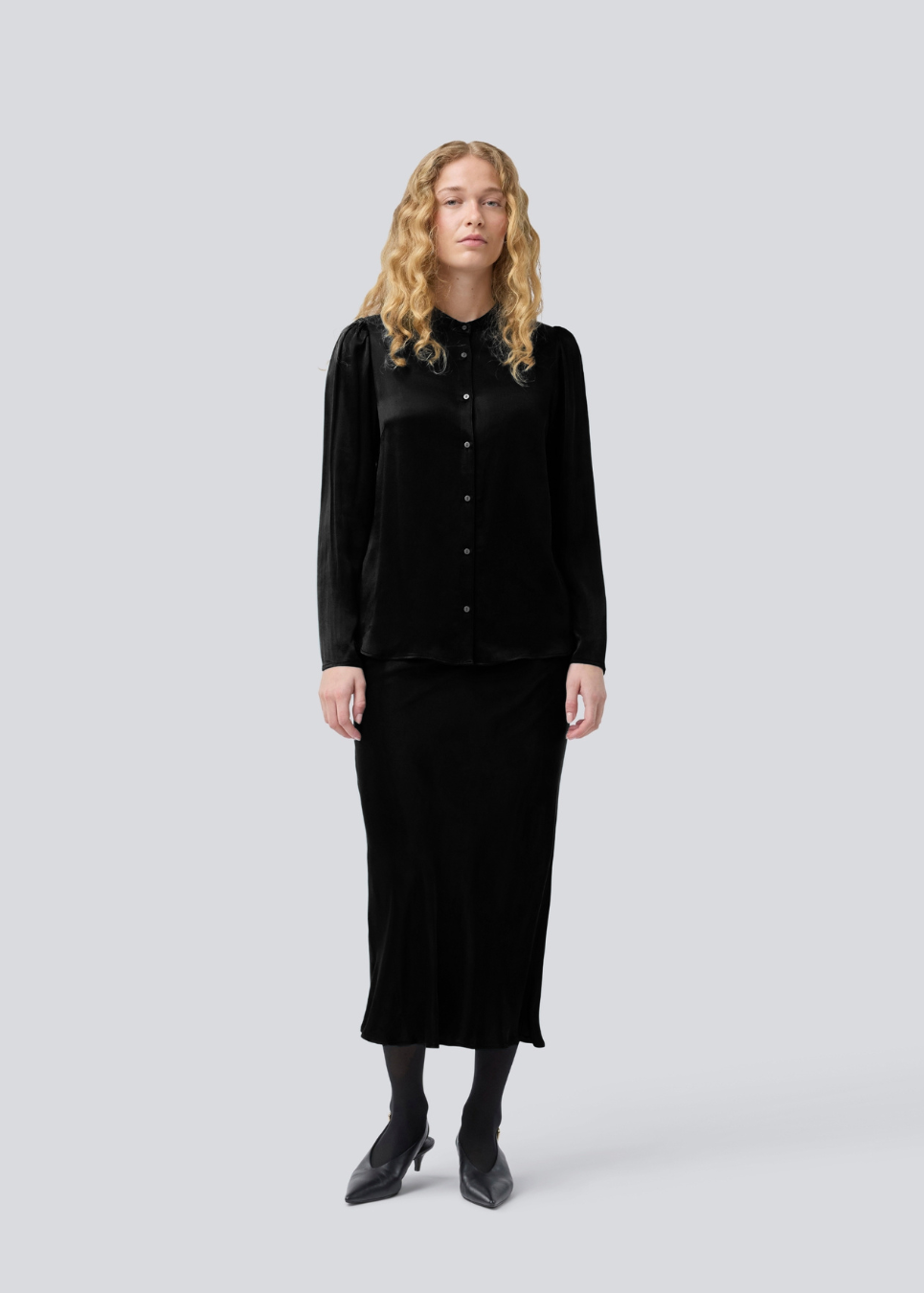 Sort lang nederdel med vidde i satin. Parveenmd skirt har en elastik i taljen. Modellen er 175 cm og har en str. s/36 på.