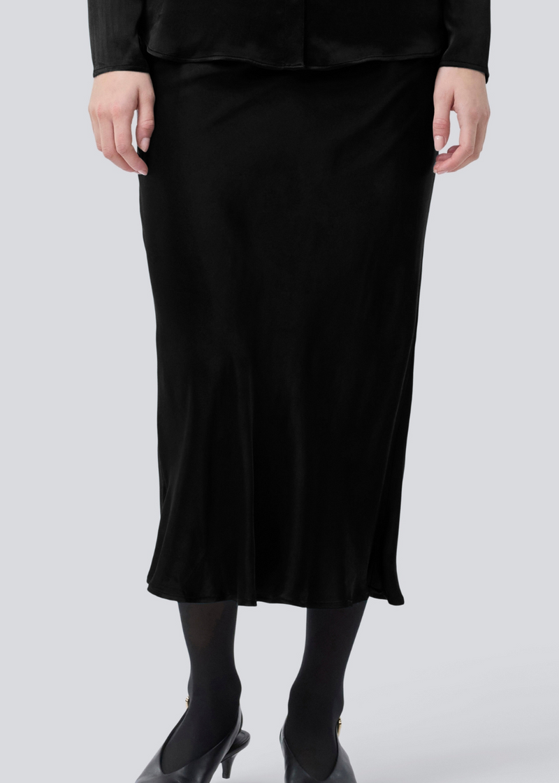 Sort lang nederdel med vidde i satin. Parveenmd skirt har en elastik i taljen. Modellen er 175 cm og har en str. s/36 på.