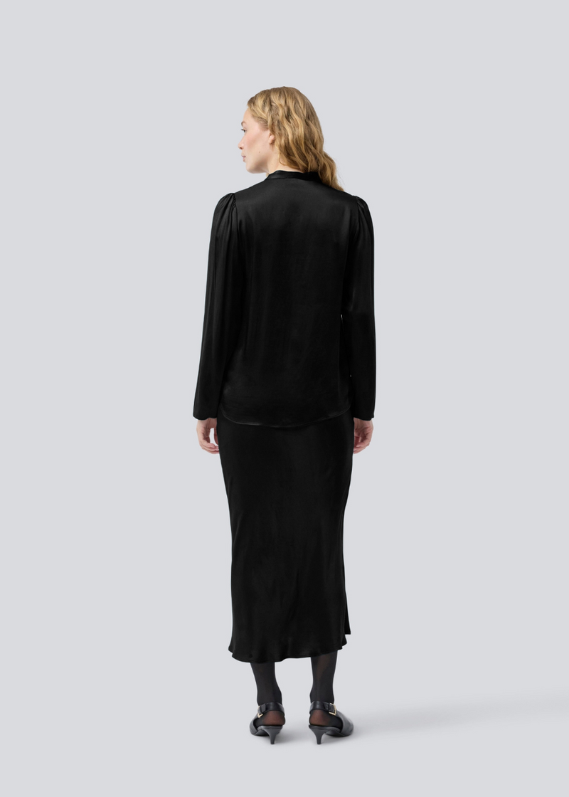 Sort lang nederdel med vidde i satin. Parveenmd skirt har en elastik i taljen. Modellen er 175 cm og har en str. s/36 på.