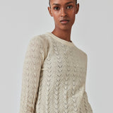 Strikket trøje i beige med hulmønster i let kvalitet med uld. CordellMD short o-neck har en afslappet cropped pasform og lange ærmer med bølgede kanter. Modellen er 175 cm og har en størrelse S/36 på.