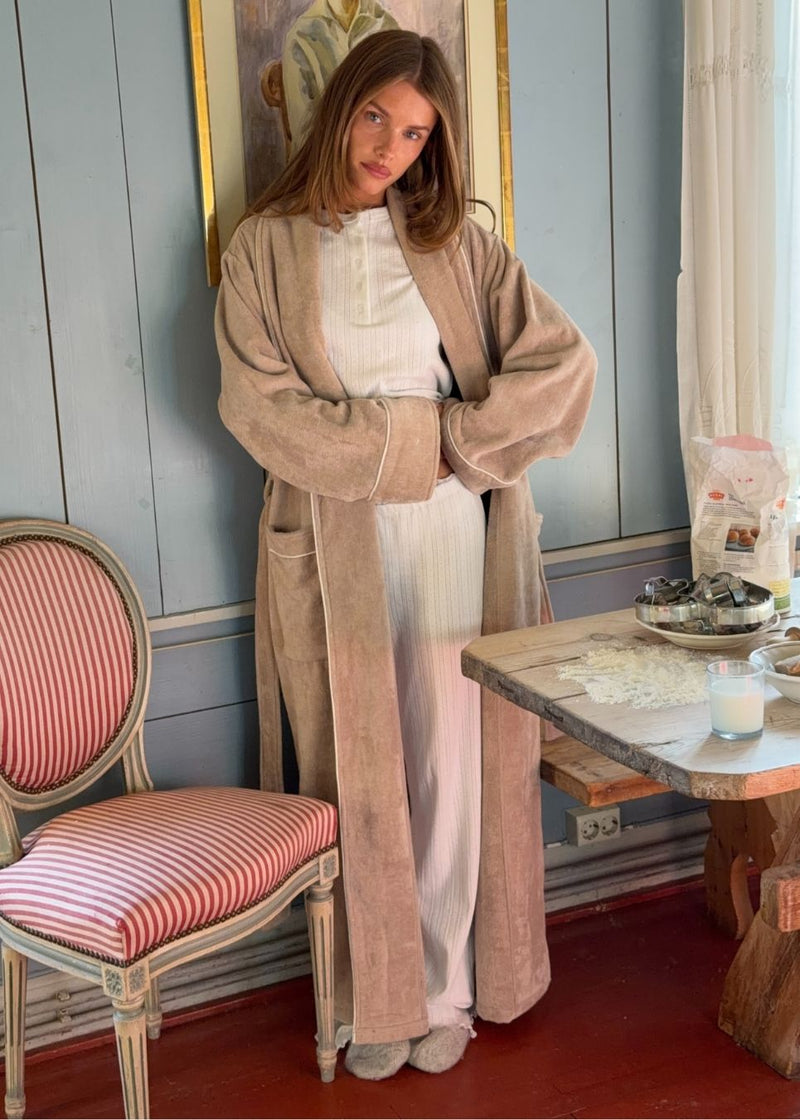 Oversize beige badekåbe i 100% økologisk bomuld. Josefinemd bathrobe har store lommer, bindebånd og kontrastkanter, der giver den et elegant touch. Badekåben har et fint og diskret logo på ryggen. Perfekt til hyggelige morgener. Josefine Vogt (165 cm) og modellen (177 cm) har begge størrelse Small på.
