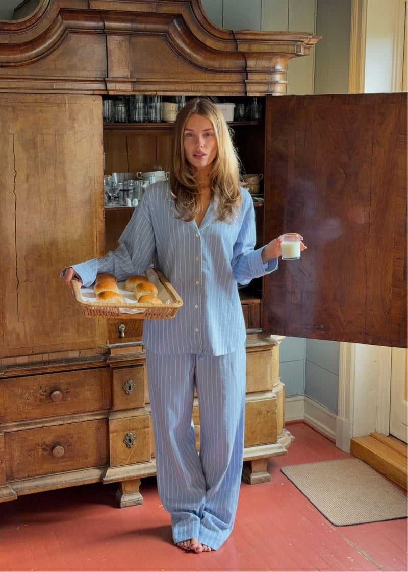 Blåt stribet pyjamas sæt i 100% bomuld. Pyjamas sælges samlet i to dele, skjorte og bukser. Josefinemd pyjamas har et klassisk fit med krave, knaplukning og snørre i bukserne. Sættet har en fin bølgekant og leveres med en matchende pose med logo. Det er ikke muligt at købe forskellige størrelser over- og underdel.&nbsp;