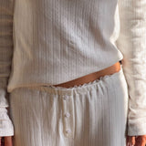 Ponitelle bukser. Josefinemd pants er feminine bukser i pointelle-bomuld med blondekant og diskret hulmønster. Blødt materiale og høj komfort gør dem perfekte til afslapning. Josefine Vogt (165 cm) og modellen (177 cm) har begge størrelse Small på.