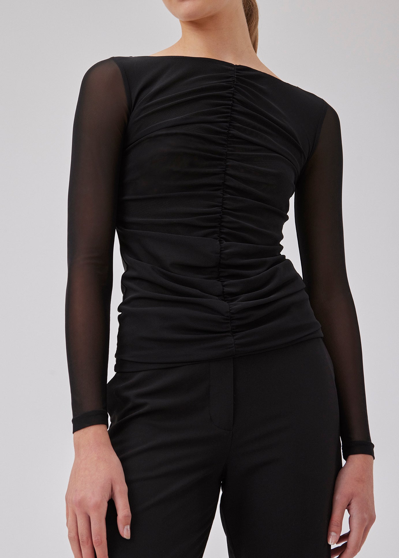 GwenMD top i sort er en tætsiddende top i mesh med rynkedetalje langs fronten. Toppen har bred halsudskæring og lange ærmer, der er en smule mere transparente end kroppen. Modellen er 175 cm og har en størrelse S/36 på.