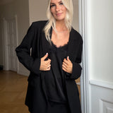 Satin top med blødt draperet fald i sort. TenjaMD top har smalle stropper og blondedetalje på front.