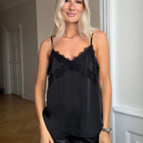 Satin top med blødt draperet fald i sort. TenjaMD top har smalle stropper og blondedetalje på front.