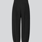Ballonbukser i sort med løs pasform i 100% genanvendt polyester. Tullemd pants har en usynlig lynlås i siden, sidelommer og elastik ved enden af benene.&nbsp;
