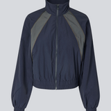 Mørkeblåt tracksuit jakke i 100% genanvendt nylon. Volmermd jacket har kontrastpaneler, høj hals og lynlåslukning fortil.&nbsp;&nbsp;