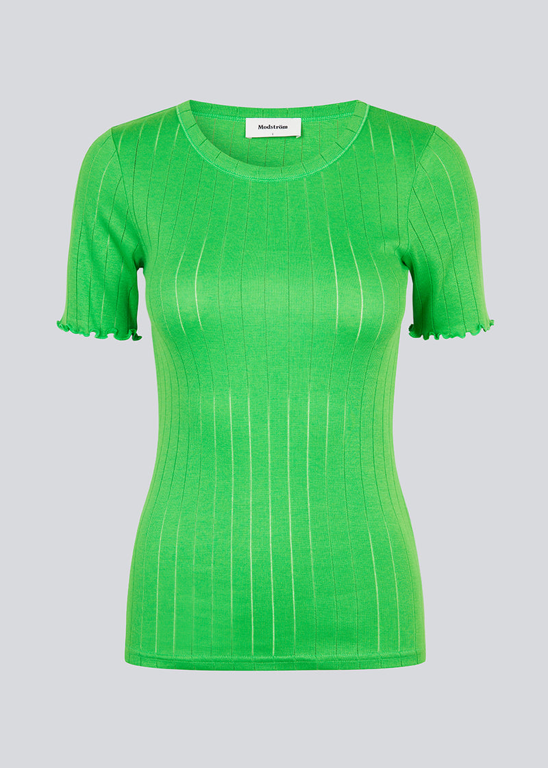 Tætsiddende t-shirt i grøn med feminin flæsekant på ærmet. Issy t-shirt er lavet i en blød jersey med et enkelt hulmønster. 