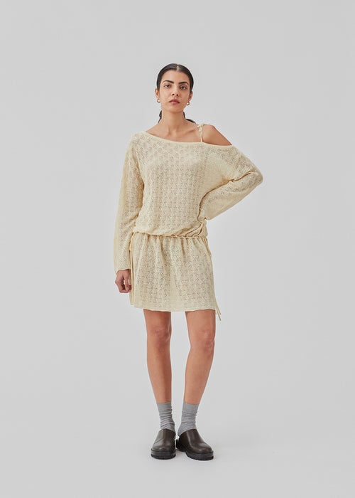 Loose fit kjole i strik med pointelle mønster. JosefineMD knit dress har asymmetriske ærmer med bindebånd over den ene skulder og justerbare bindebånd i taljen. Modellen er 177 cm og har en størrelse S/36 på.