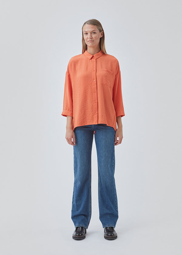 Smuk skjorte i et klassisk design i orange. Alexis shirt har krave og bliver knappet fortil. Skjorten har 3/4 lange ærmer og en enkelt brystlomme, som er med til at give detalje. Modellen er 174 cm og har en størrelse S/36 på