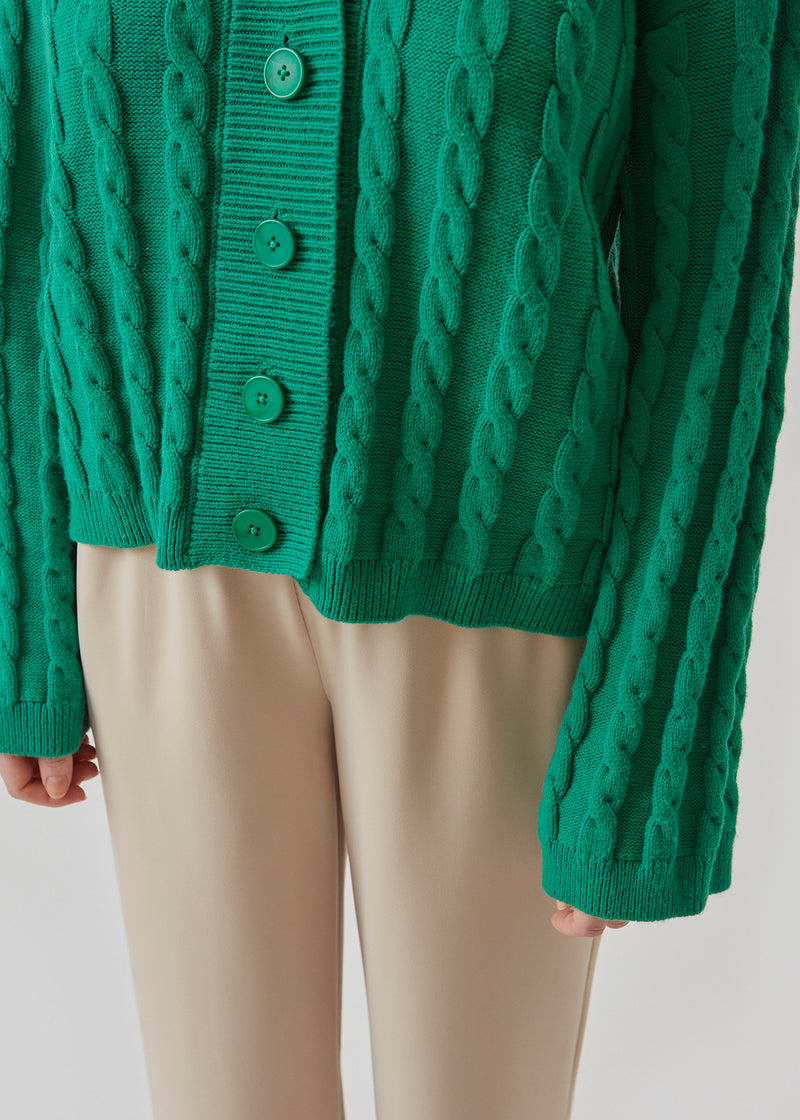 Cardigan i grøn i kabelstrik med lange ærmer. AliceMD cardigan har v-udskæring og knapper foran. Ribkanter langs udskæring, knapper, manchet og bund.
