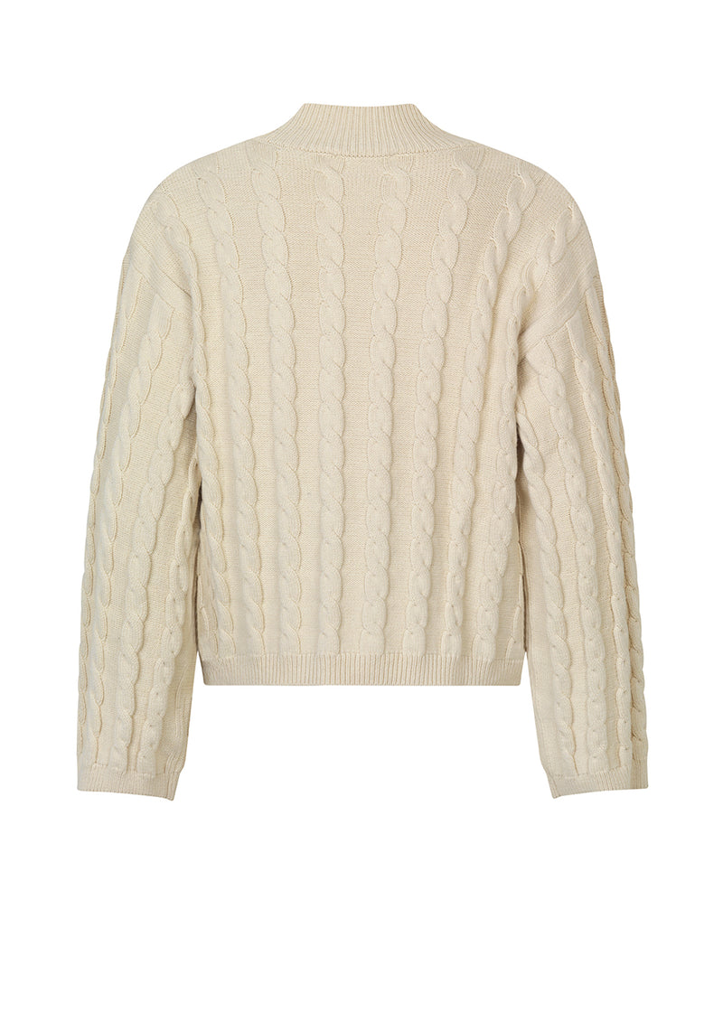 Cardigan i beige i kabelstrik med lange ærmer. AliceMD cardigan har v-udskæring og knapper foran. Ribkanter langs udskæring, knapper, manchet og bund.