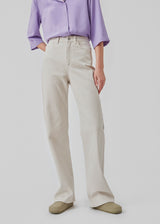 Jeans i farvet økologisk bomuldsdenim i farven summer sand. AmeliaMD jeans har en høj talje, fem lommer og lige, vide ben. Gylp med knap og lynlås. Modellen er 177 cm og har en størrelse S/36 på.