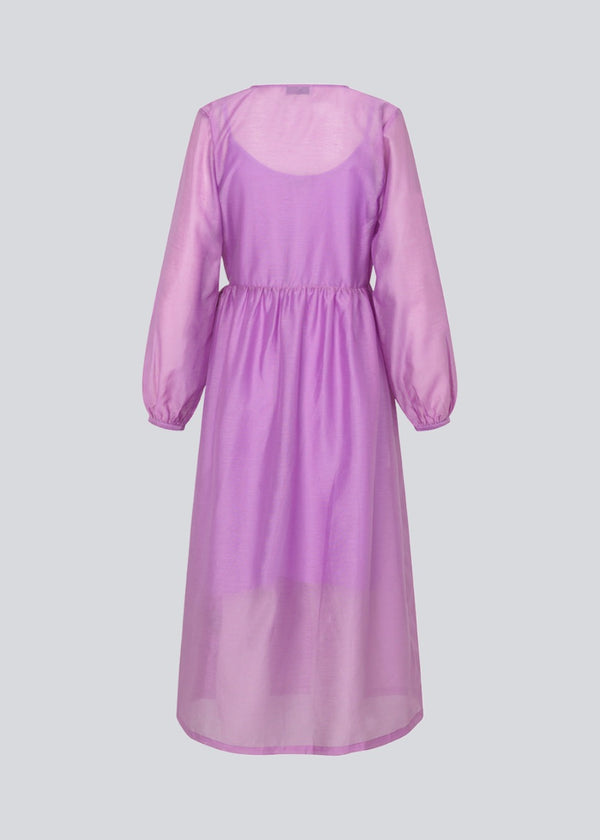 Mellemlang kjole i lilla i luftig hør-kvalitet, der er en smule gennemsigtig. AmoraMD dress har lange ballonærmer, v-udskæring og wrap-effekt med bindebånd. Underkjole medfølger.