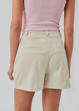 Shorts i beige med brede ben og mellemhøj talje. AnkerMD shorts har pressefolder, gylp med lynlås og knap, skrå sidelommer og paspolerede baglommer.  Modellen er 174 cm og har en størrelse S/36 på.