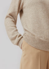 Fintstrikket trøje i beige i en mere ansvarlig kvalitet. AnnaMD o-neck har en smal pasform med lange ærmer og rund hals. Ribkant i halsen, ærmegab og kant forneden