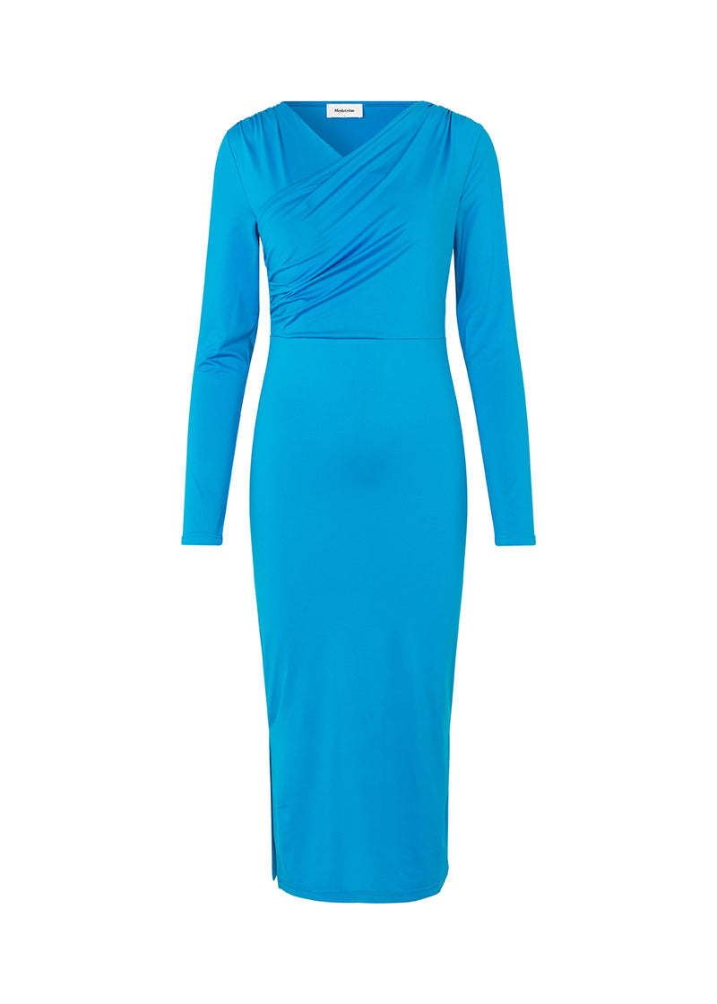 Tætsiddende kjole i flot blå med langt skørt med slidser i siderne. ArniMD dress har en høj v-udskæring med flatterende wrap-detalje over brystet.