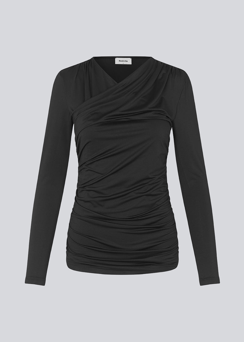 Langærmet bluse i sort med kropsnær pasform og i elastisk materiale. ArniMD top har en høj v-udskæring med wrap-effekt foran.