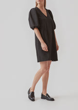 Kort kjole i sort med afslappet pasform og v-udskæring. Ærmerne på AshaMD dress er korte og voluminøse med elastikkant.  Materiale: 100% Polyester  Foer: 100% Polyester